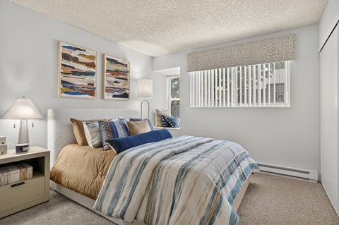 A bedroom with a bed, nightstand, and pictures on the wall.