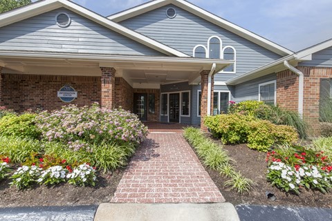 A building with a grey roof and a brick pathway leading to the entrance.