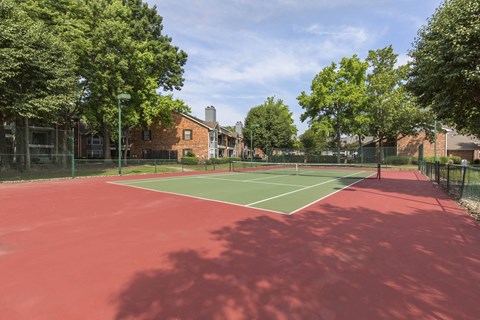 A tennis court with a red surface and white lines.