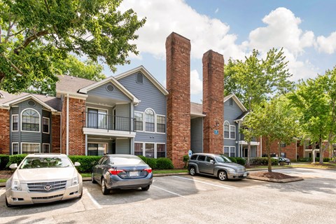 A building with a grey roof and a parking lot with cars.