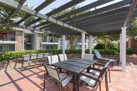 A patio with a table and chairs under a pergola.