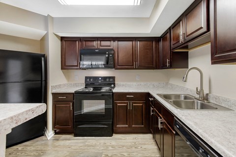 A kitchen with a black oven and brown cabinets.