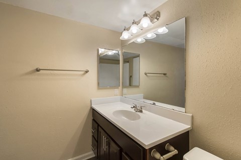 A bathroom with a sink, mirror, and towel bar.