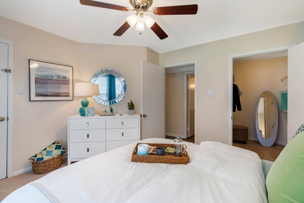 A bedroom with a white bed and a ceiling fan.