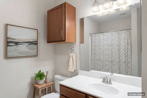 A bathroom with a white sink and a brown cabinet.