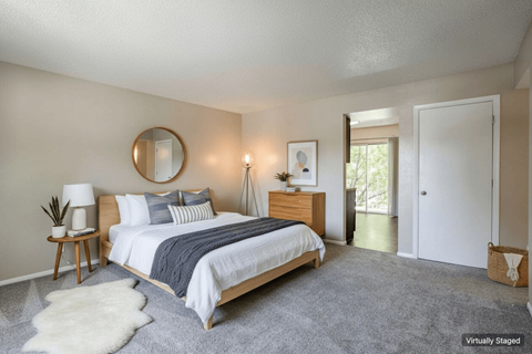 A bedroom with a bed, nightstand, and a mirror on the wall.