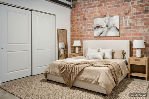 A bedroom with a brick wall and a bed with a beige comforter.