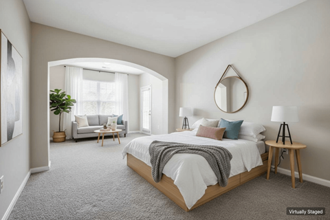 A bedroom with a large bed and a couch in the background.