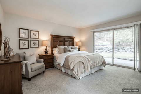 A bedroom with a large bed, a chair, and a nightstand with a lamp.
