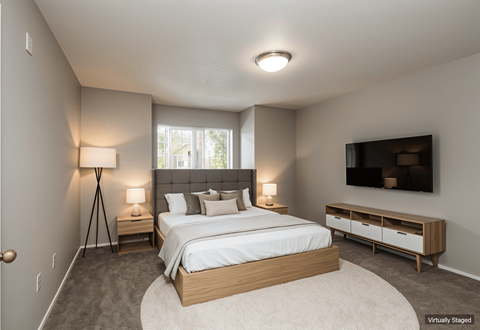 A bedroom with a large bed and a TV on the wall.