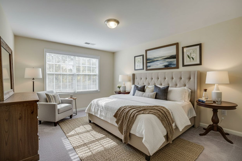 A bedroom with a large bed and a wooden dresser.
