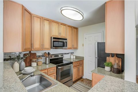 A kitchen with wooden cabinets and a black refrigerator.