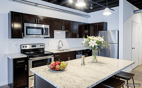A kitchen with a granite countertop and a bowl of fruit on it.