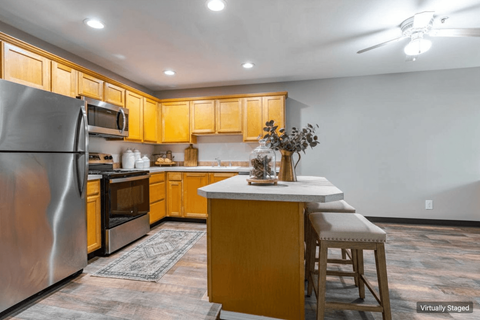 A kitchen with wooden cabinets and a stainless steel refrigerator.