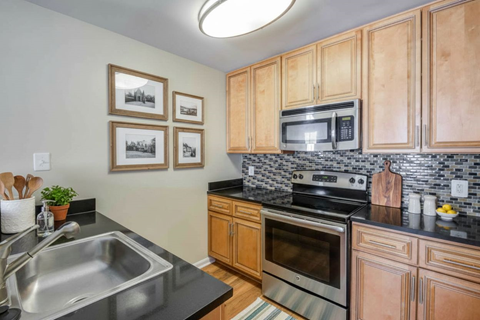 A kitchen with wooden cabinets and a black countertop.