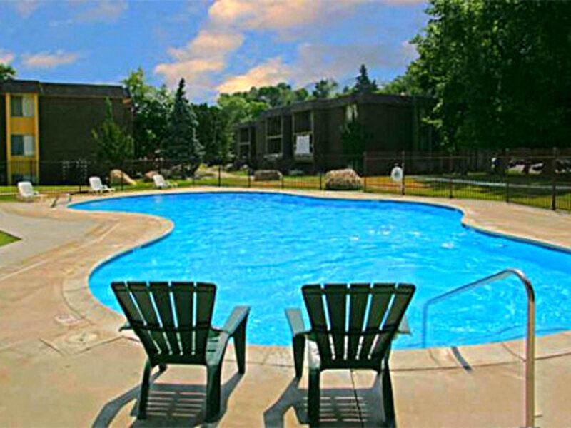a large swimming pool with two chairs next to it