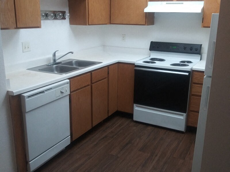 an empty kitchen with white appliances and wooden cabinets