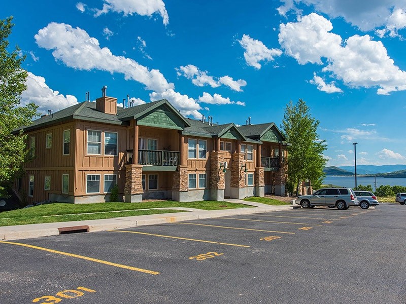 an apartment building with a parking lot and a lake in the background