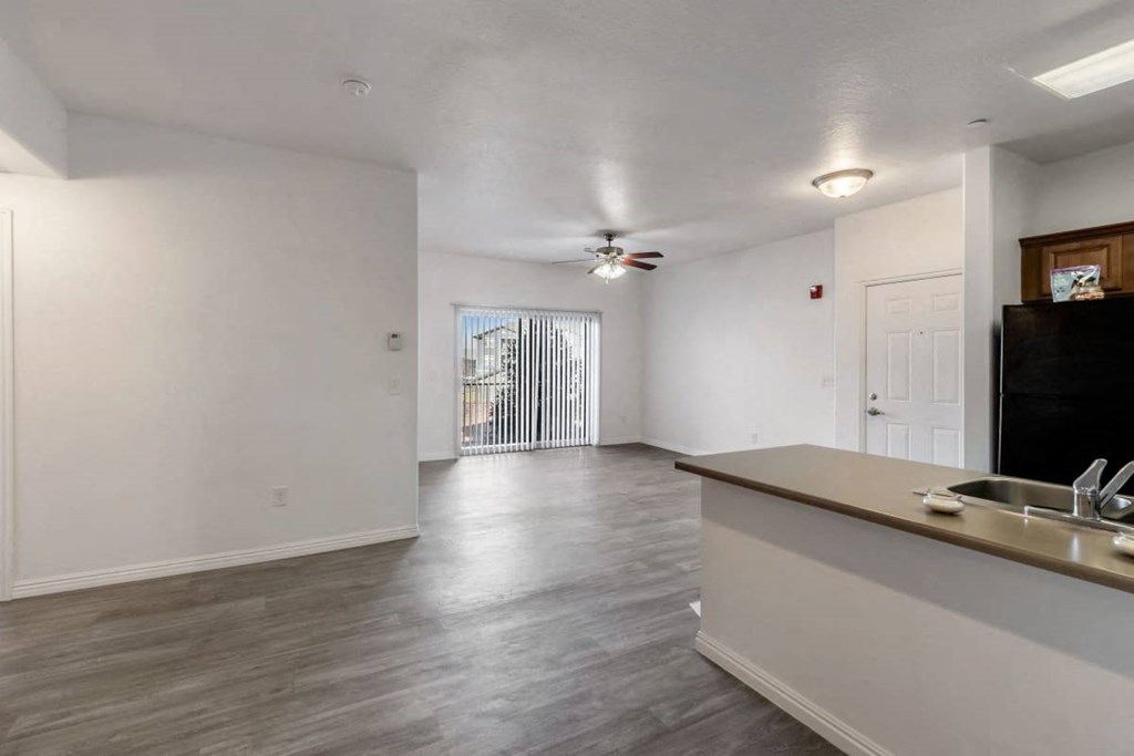 an empty living room and kitchen with a ceiling fan