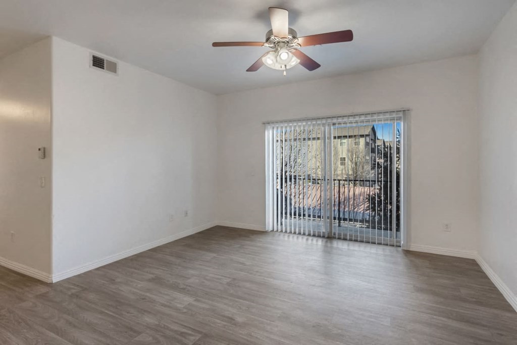 a living room with a large window and a ceiling fan