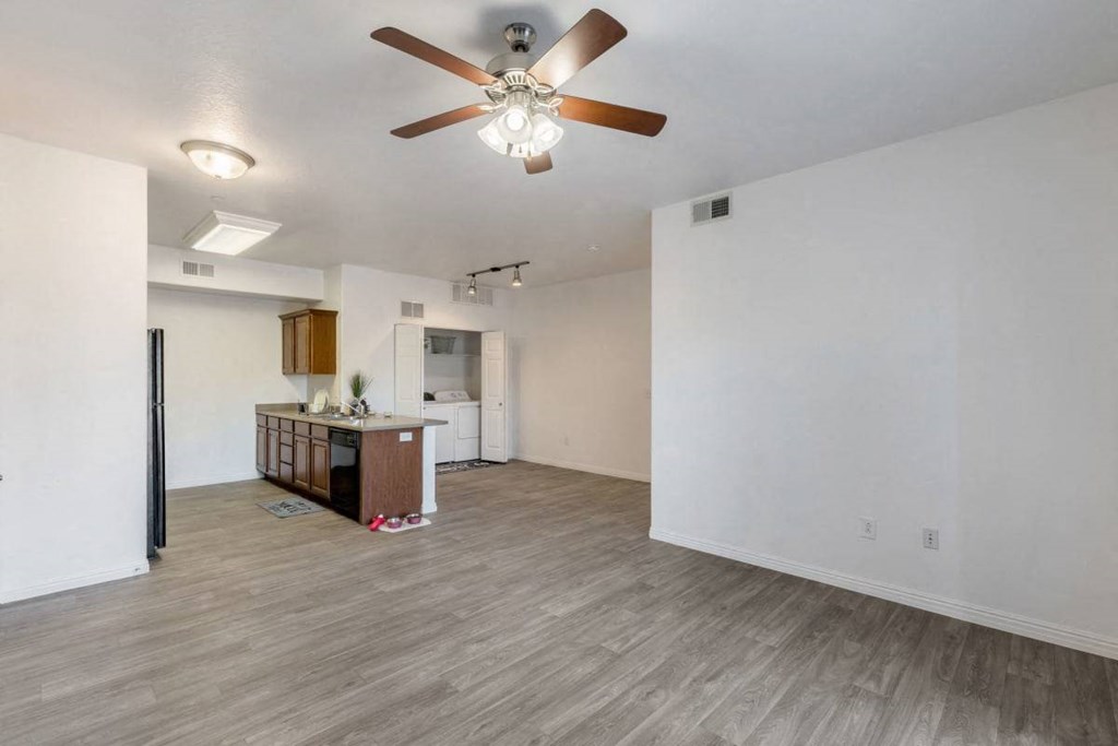 an empty living room and kitchen with a ceiling fan