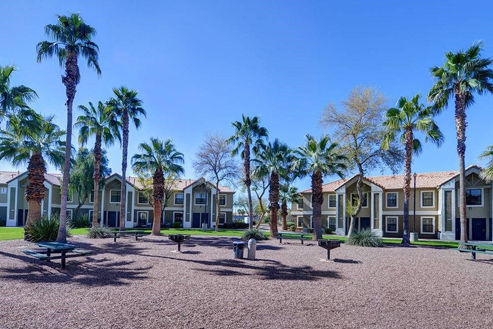 a courtyard with benches and palm trees in front of houses
