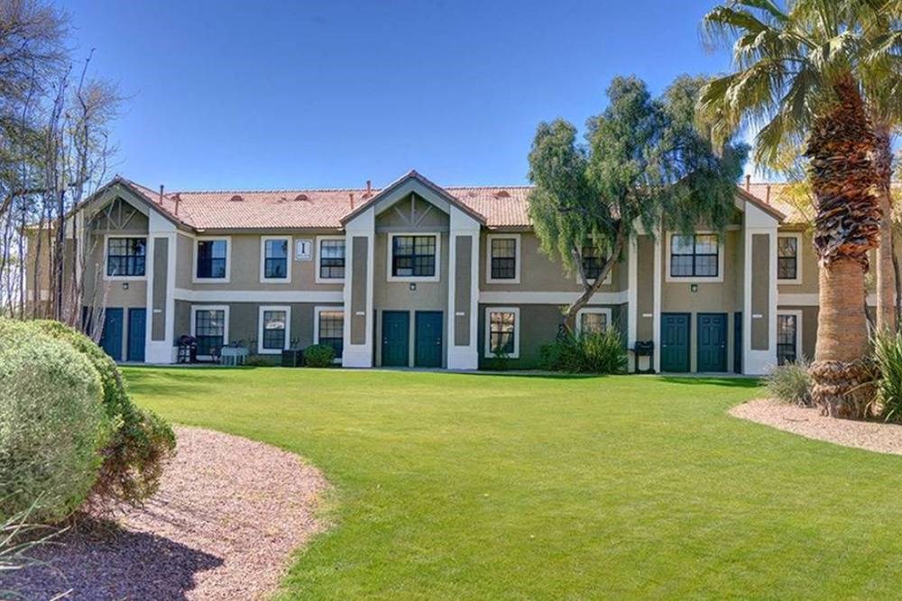 a large house with a green lawn and palm trees