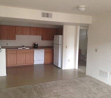 an empty kitchen with wooden cabinets and a white refrigerator