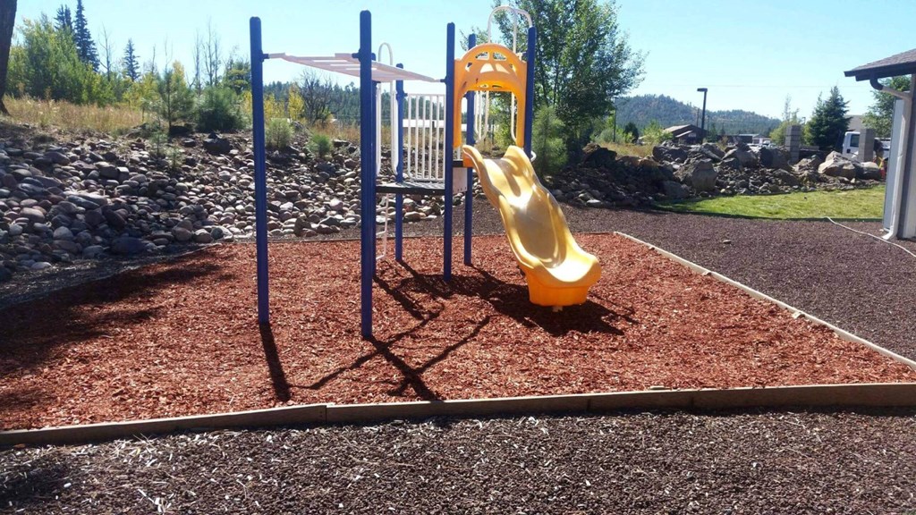 a playground with a yellow slide in a park