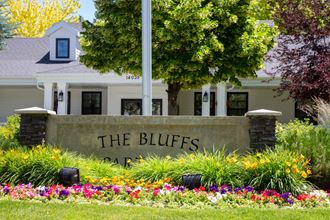 the bluff apartments sign in front of a building with flowers