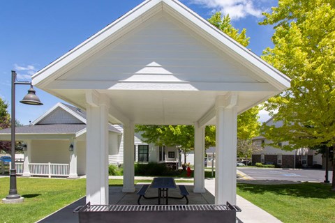 a pavilion with a picnic table in front of a house