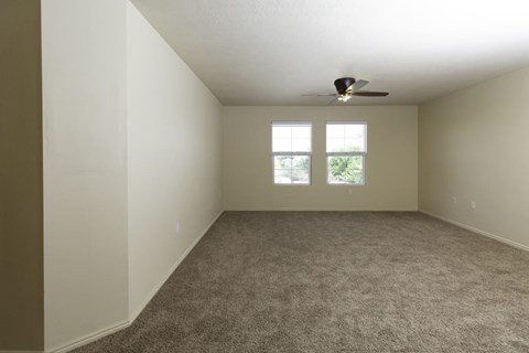 an empty living room with a ceiling fan and a window