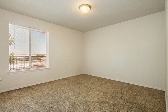 an empty living room with a window and carpet