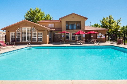 a swimming pool with umbrellas in front of a house