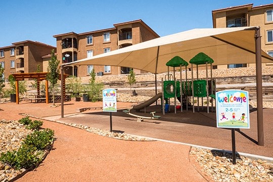 a playground with a picnic shelter and buildings in the background