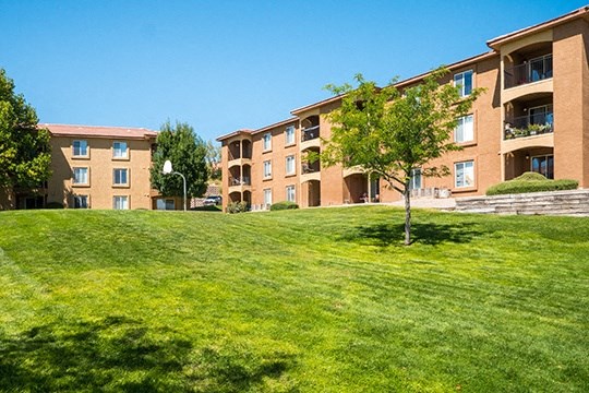 a green lawn in front of a brick apartment building
