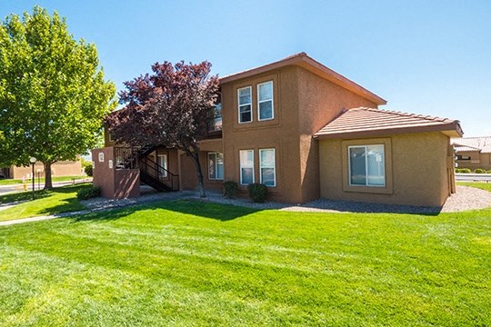 a brown house with a green lawn and a tree