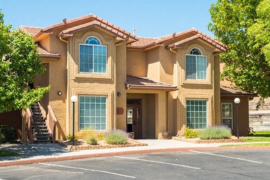 a brown house with a driveway and trees