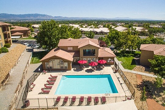 an aerial view of a swimming pool and patio with umbrellas