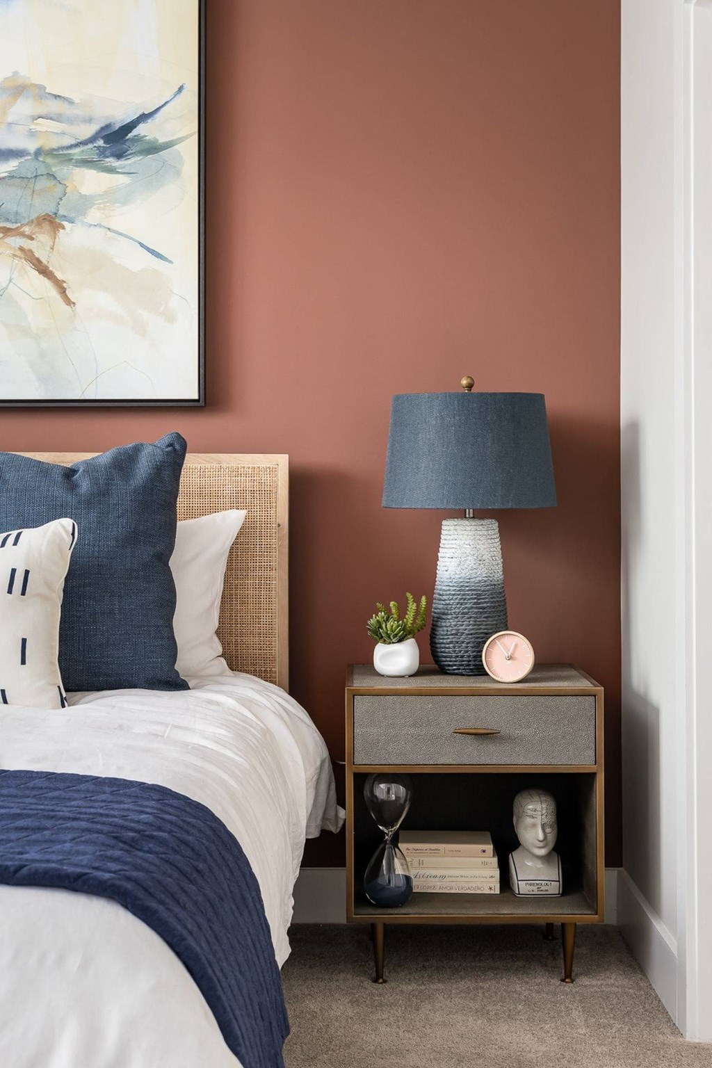 a bedroom with a bed and a nightstand with a lamp and a painting