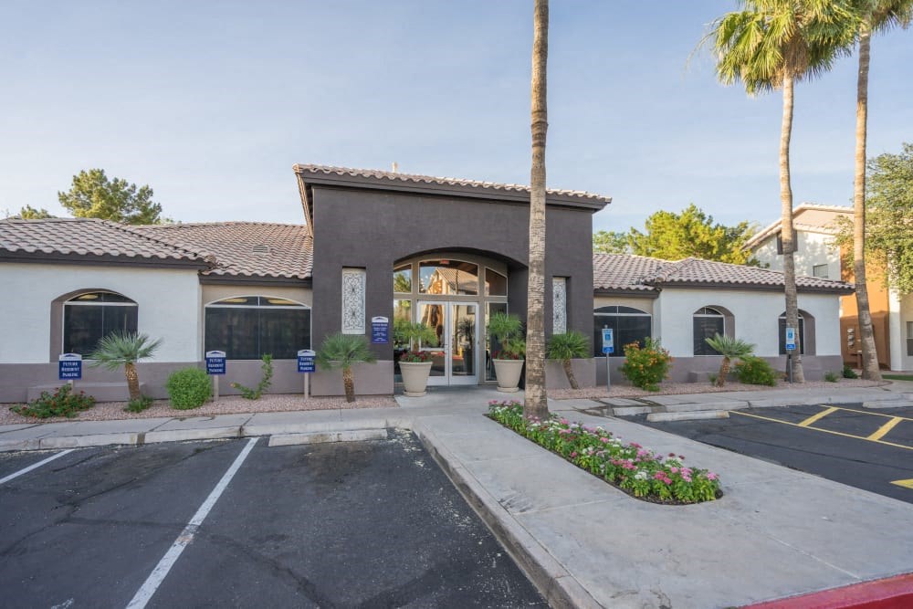 the front of a building with palm trees and a parking lot