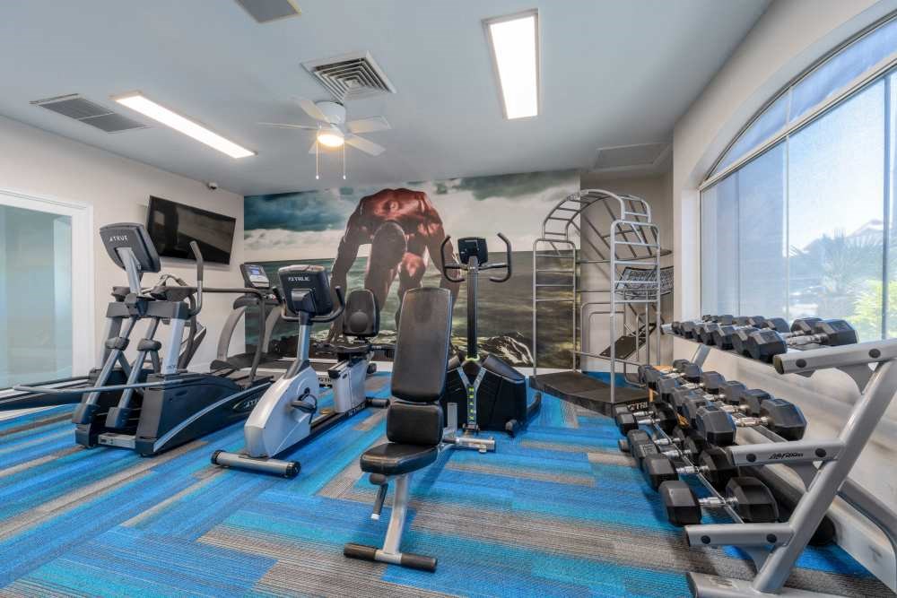 a gym with cardio equipment and a mural of a man on the wall