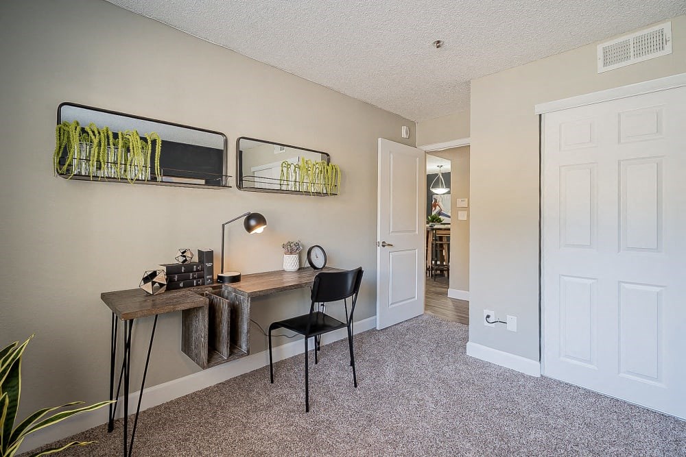 an office with a desk and a door to a living room
