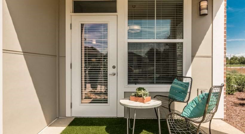 a patio with two chairs and a table in front of a door