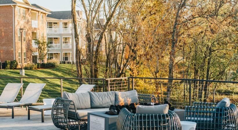 a patio with chairs and a couch in front of an apartment building