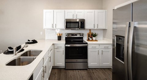 A modern kitchen with white cabinets and stainless steel appliances.