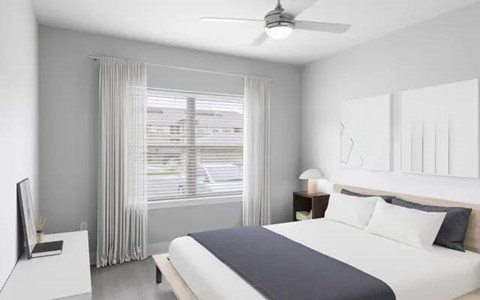 A bedroom with a bed, nightstand, and window with curtains.
