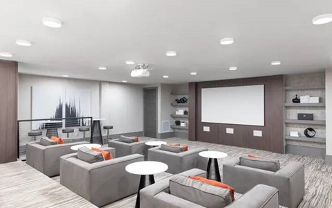 A modern living room with grey couches and a large screen on the wall.