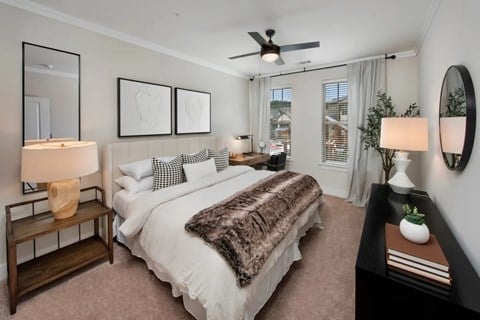 A bedroom with a large bed, a ceiling fan, and a window with curtains.