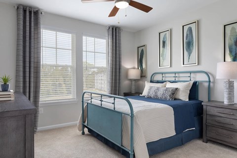 A bedroom with a bed, nightstand, and a ceiling fan.